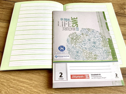 aufgeschlagenes A5-Schulheft mit der Lineatur 2 fürs 2. Schuljahr mit grünem Kontrasthintergrund