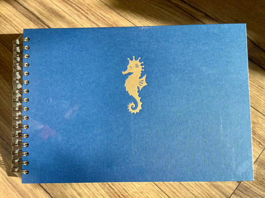 blaues Spiral-Fotobuch mit goldenem Seepferchen auf dem Cover