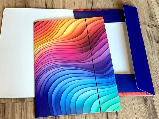 In grafischen Wellen in Regenbogenfarben bedruckte Sammelmappe mit Gummizug aus Recyclingpappe.
Erhältlich bei Polly Paper - umweltfreundlicher Schulbedarf in Berlin-Mitte