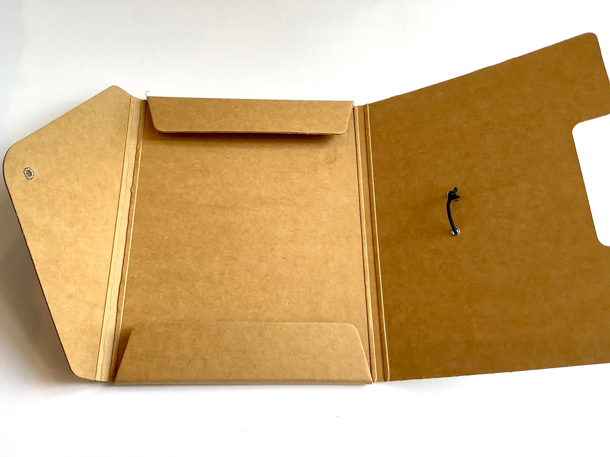 offene braune Sammelmappe in A5, die mit einem schmwarzen Gummiband über einem Metallhäkchen verschlossen wird, edles Design, kraftfarben