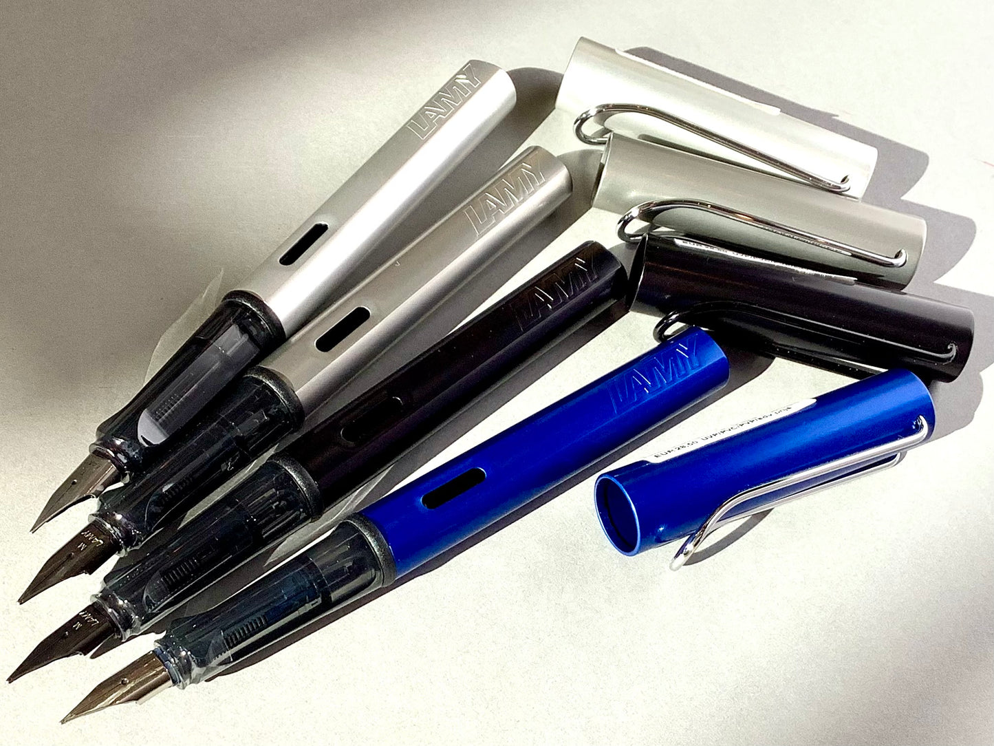 Füllhalter von LAMY aus Aluminium in blau, schwarz und silber (Griffstück aus transparentem Kunststoff). 
Erhältlich bei Polly Paper Schreibwaren in Berlin-Mitte