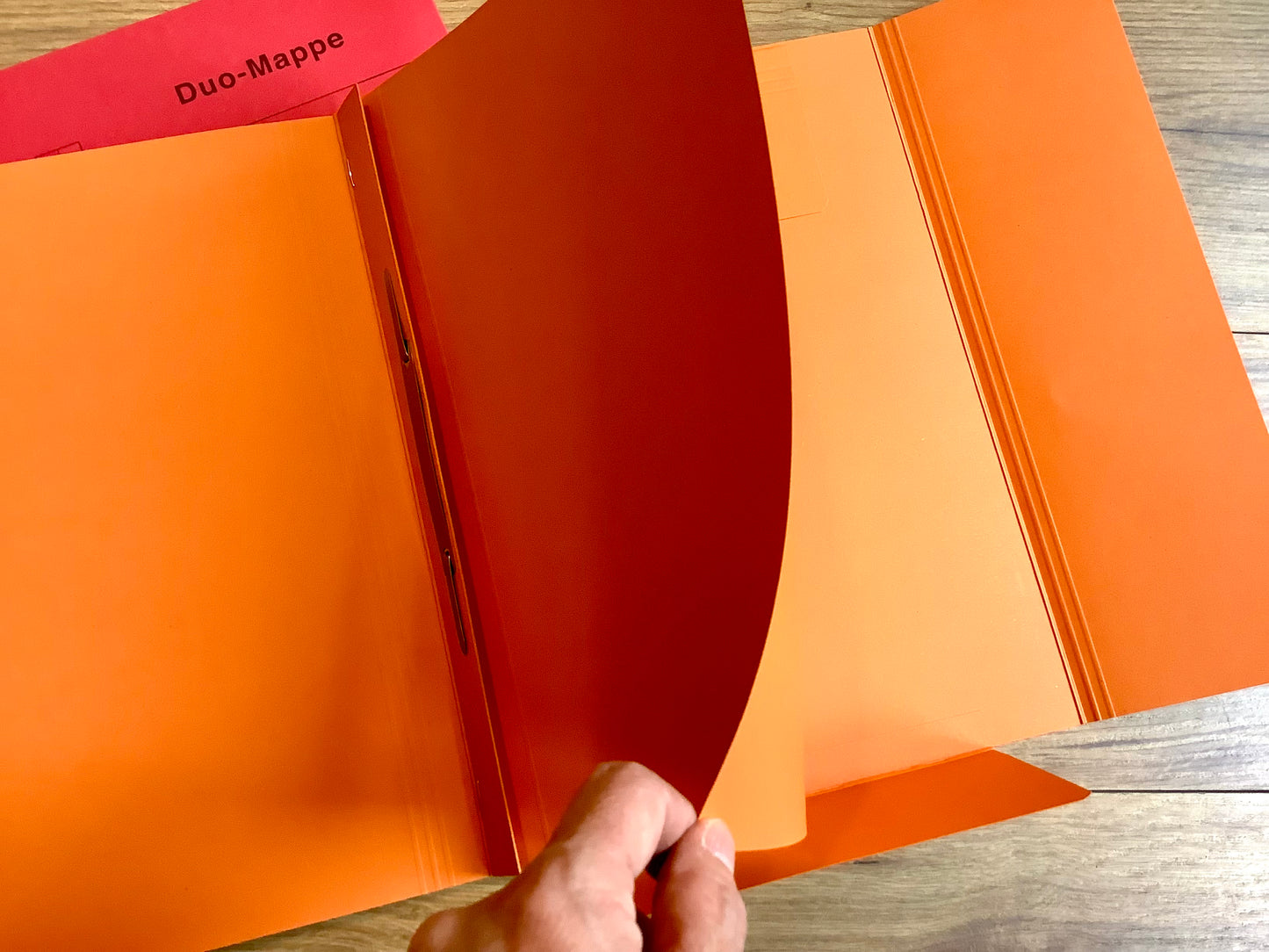 Praktische Kombi: ein Schnellhefter, der hinten daran noch eine Einschlagmappe hat. Orange.