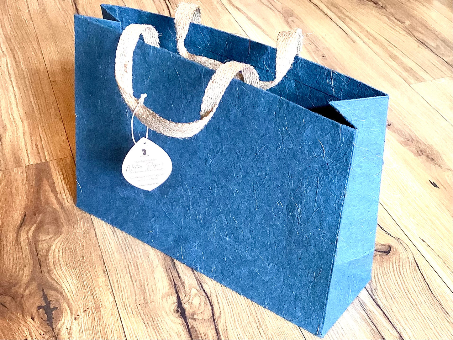 Blaue Geschenktasche aus Naturpapier mit Kokosfasern und Jute-Henkeln.