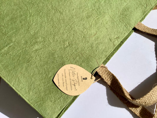 Grüne Geschenktasche aus Naturpapier mit Kokosfasern und Jute-Henkeln.