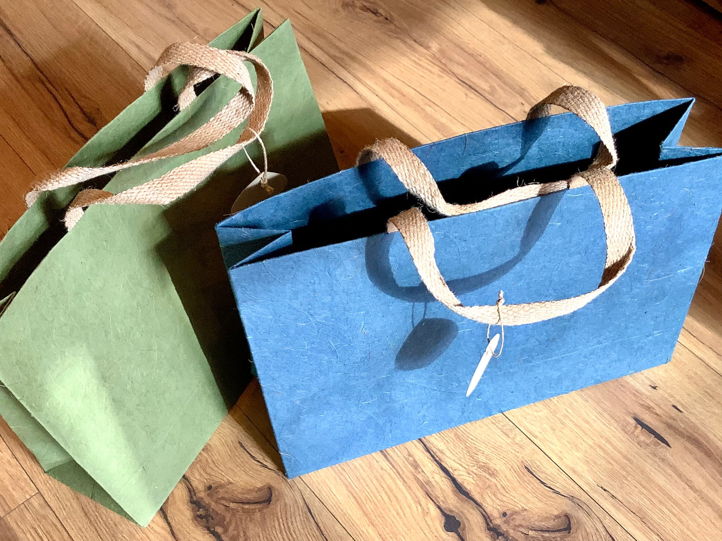 Blaue und grüne Geschenktasche aus Naturpapier mit Kokosfasern und Jute-Henkeln.