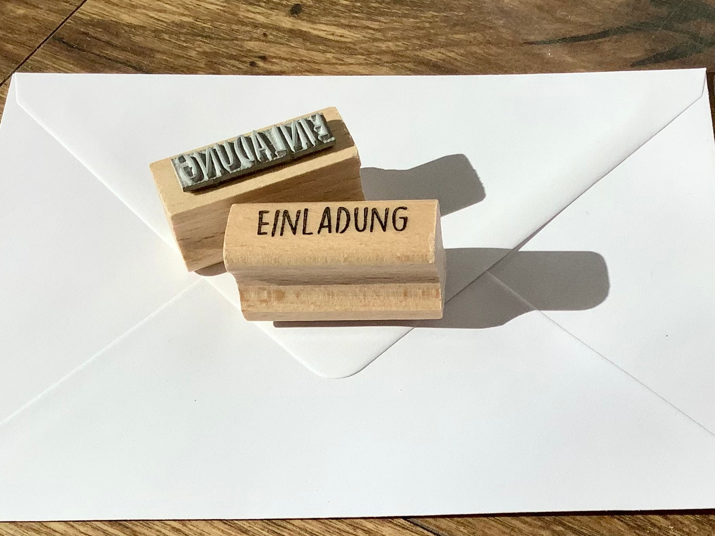 Länglicher Holzstempel mit dem Stempeltext EINLADUNG in Großbuchstaben.
