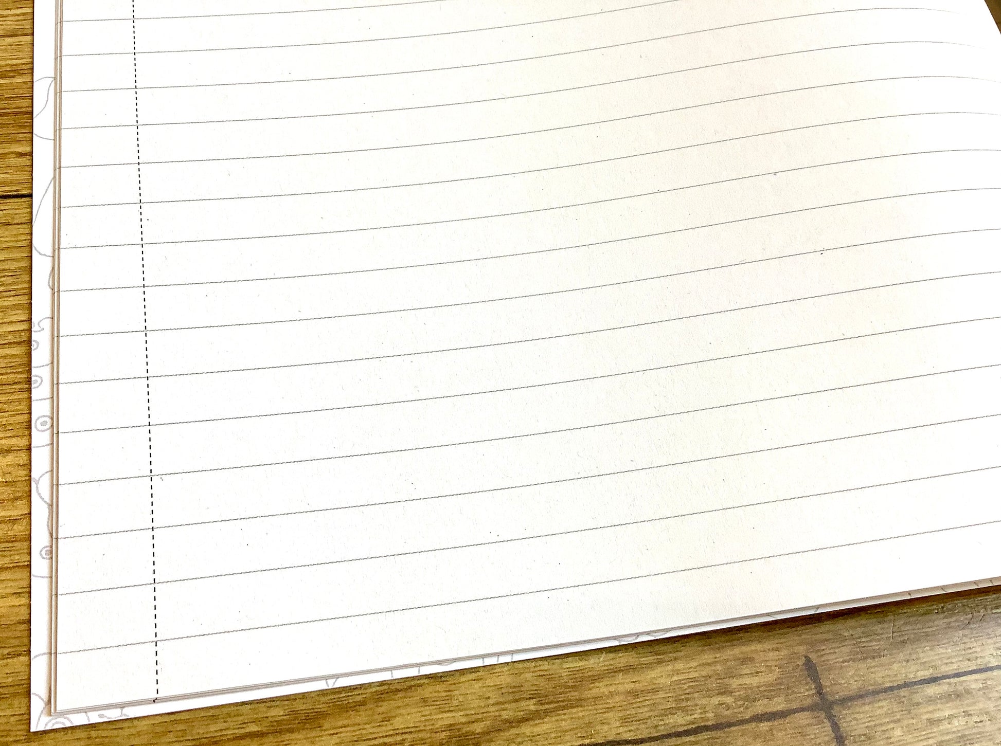 Ein aufgeschlagenes liniertes Schulheft mit schmalem Rand, durch eine Linie abgetrennt.