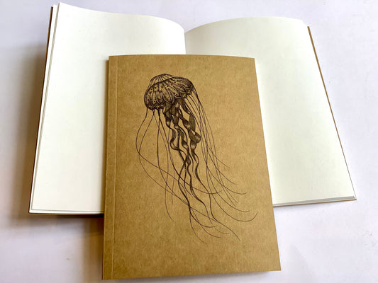 kraftfarbenes kleines Notizbuch mit einer schwarz gezeichneten filigranen Tiefseequalle auf dem Cover, innen weißes Papier, unliniert. Recyclingpapier.