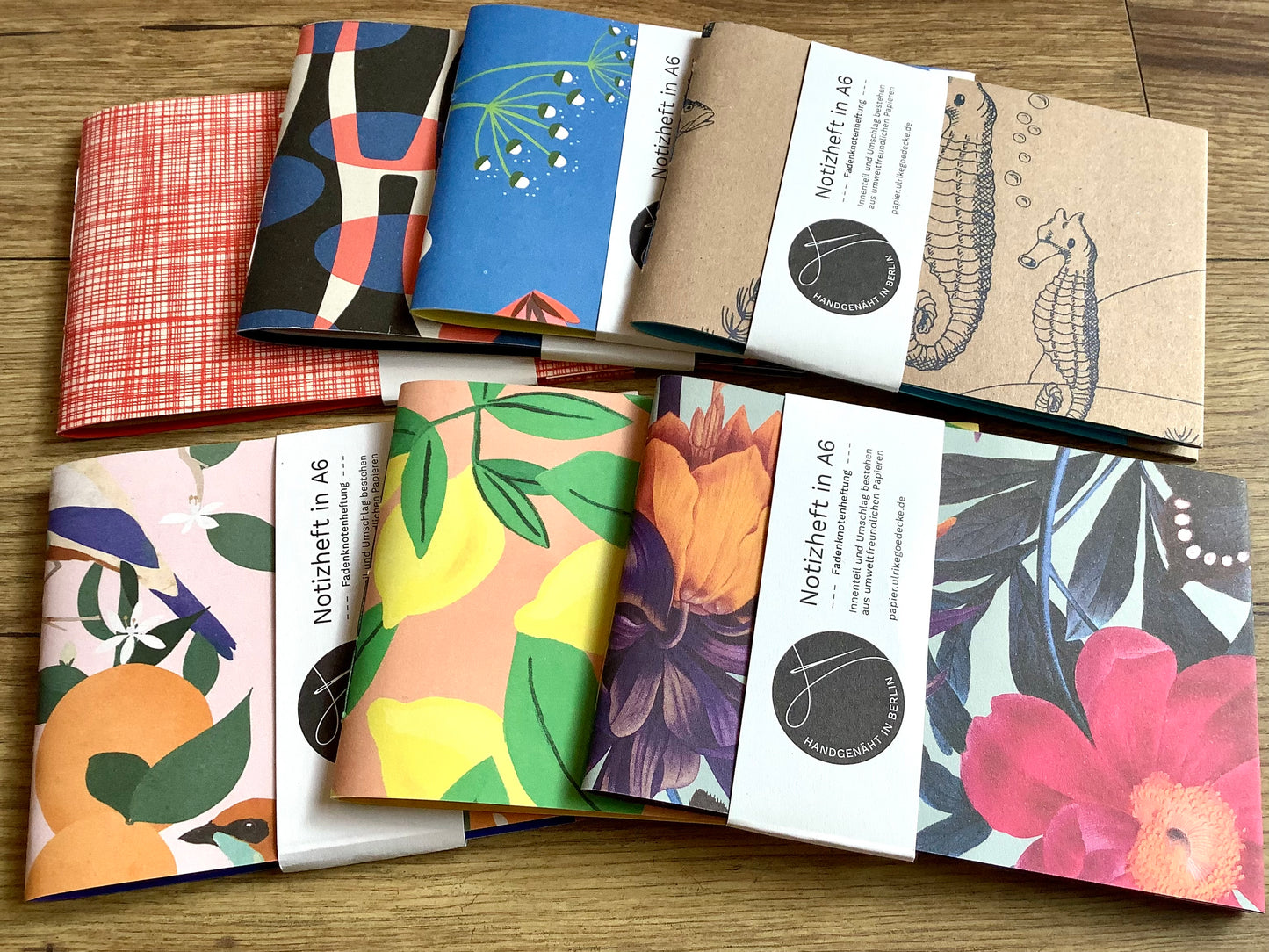 Fadengeknüptes Notizheft im A6-Querfomat mit einem Cover aus bunt gemustertem Papier, innen unliniertes farbiges Recyclingpapier