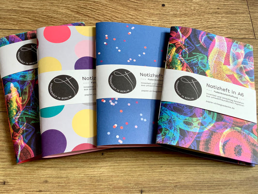 Fadengeknüptes Notizheft im A6-Fomat mit einem Cover aus bunt gemustertem Papier, innen unliniertes farbiges Recyclingpapier