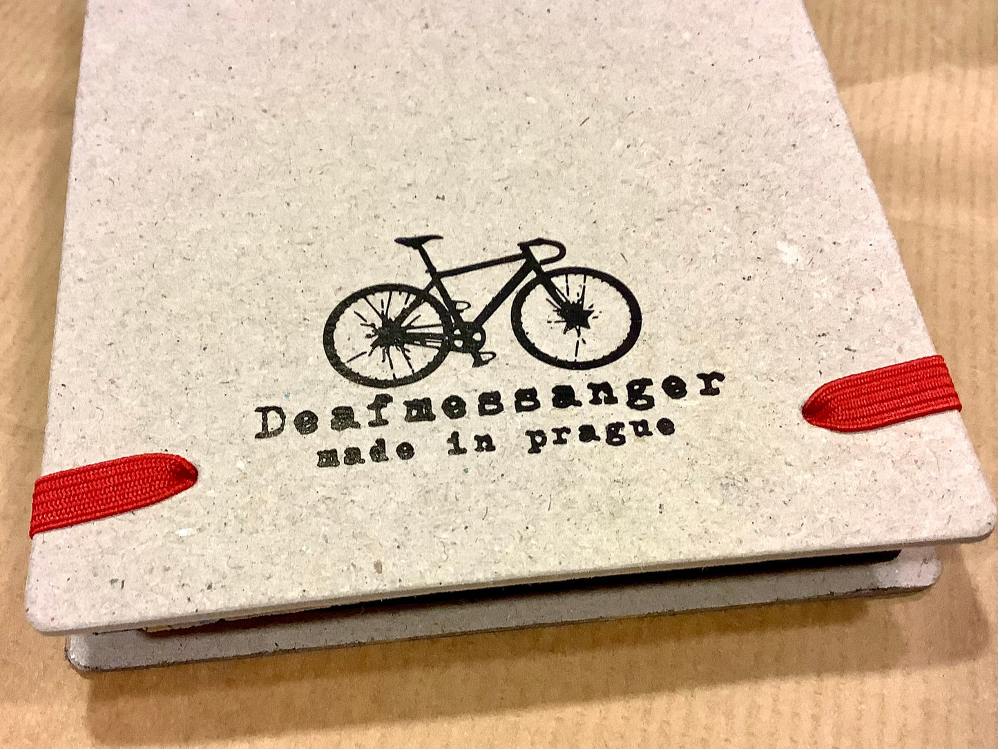 Rückseite des Notizblocks "Reporter" , graue Pappe mit aufgedrucktem schwarzen Fahrrad und dem Herstellernamen "Deafmessanger" made in Prague. Erhältlich bei Polly Paper in Berlin-Mitte