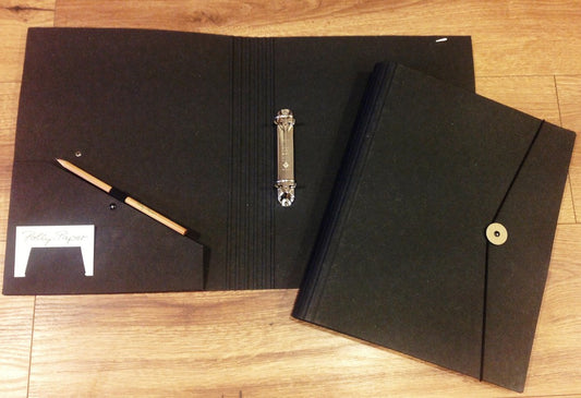 Schwarze Tagungsmappe mit Ringbuch-Mechanik und Gummizug zum Verschließen.
Bei Polly Paper - umweltfreundlicher Bürobedarf in Berlin-Mitte