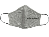 hellgraue Stoffmaske für Kinder mit dem schwarzen Aufdruck: smile inside